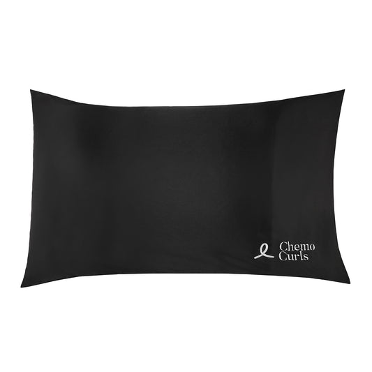 An image of a black satin pillowcase with a sleek and smooth surface. The soft black color of the pillowcase exudes elegance and sophistication. The Chemo Curls logo is skillfully embroidered in white thread on the lower left corner, adding a personalized touch. The satin fabric catches the light, creating a subtle sheen and highlighting the luxurious texture. This image portrays a sense of comfort, style, and attention to detail.